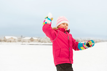 Image showing happy girl playing and throwing snowball in winter