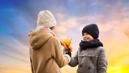 Image showing kids with autumn maple leaves over sky background