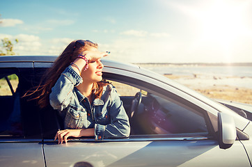 Image showing happy teenage girl or young woman in car