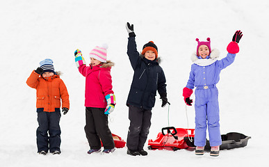 Image showing happy kids with sleds waving hands in winter