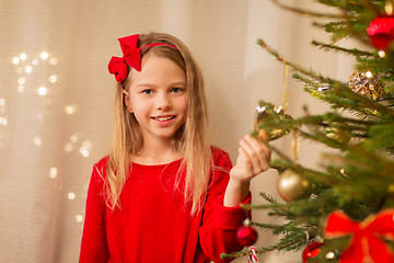 Image showing happy girl in red decorating christmas tree