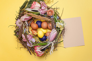 Image showing Easter card. Painted Easter eggs in nest on yellow background