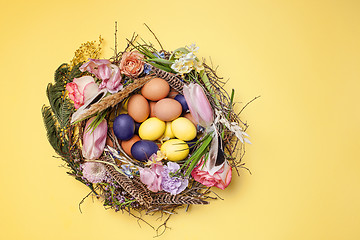 Image showing Easter card. Painted Easter eggs in nest on yellow background