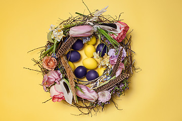 Image showing Easter card. Painted Easter eggs in nest on yellow background