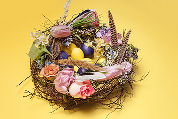 Image showing Easter card. Painted Easter eggs in nest on yellow background