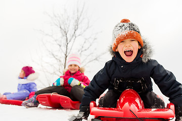 Image showing happy kids sliding on sleds in winter