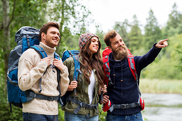 Image showing happy friends or travelers with backpacks hiking