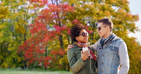 Image showing couple listens music by smartphone in autumn park