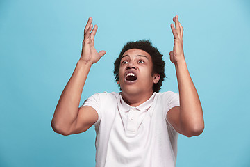 Image showing The young emotional angry man screaming on blue studio background