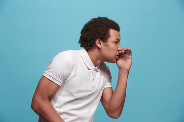 Image showing Isolated on blue young casual man shouting at studio