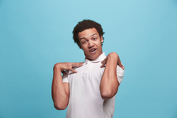 Image showing Beautiful male half-length portrait isolated on blue studio backgroud. The young emotional surprised man