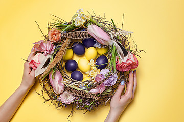 Image showing Easter card. Painted Easter eggs in nest on yellow background