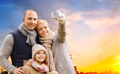 Image showing family taking selfie by camera over sunset in city