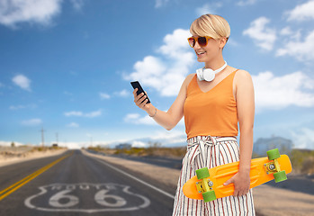 Image showing teenage girl with skateboard and smartphone