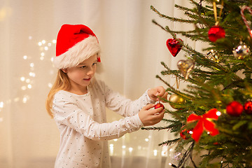 Image showing happy girl in santa hat decorating christmas tree