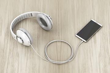 Image showing Big white headphones and smartphone on wood table