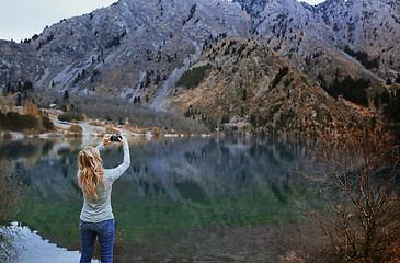 Image showing Woman making mobile photo at the mountain lake