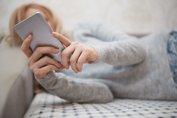 Image showing Woman with smartphone laying on a sofa