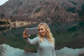 Image showing Smiling woman makes selfie at the mountain lake