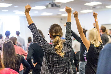 Image showing Participants of interactive motivational speech feeling empowered and motivated, hands raised high in the air.