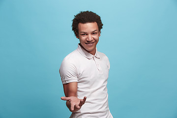 Image showing Beautiful male half-length portrait isolated on blue studio backgroud. The young emotional surprised man