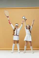 Image showing Portrait of two girls as tennis players holding tennis racket. Studio shot.