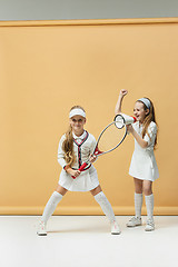 Image showing Portrait of two girls as tennis players holding tennis racket. Studio shot.