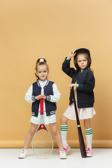 Image showing Portrait of two girls as tennis players holding tennis racket. Studio shot.