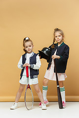 Image showing Portrait of two girls as tennis players holding tennis racket. Studio shot.