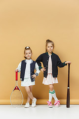 Image showing Portrait of two girls as tennis players holding tennis racket. Studio shot.