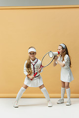 Image showing Portrait of two girls as tennis players holding tennis racket. Studio shot.