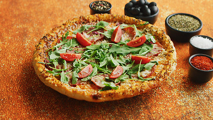 Image showing Tasty pizza on a rusty background with spices, herbs and vegetables