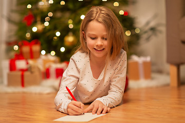 Image showing smiling girl writing christmas wish list at home