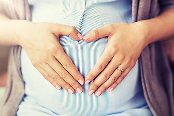 Image showing close up of pregnant woman making heart on belly