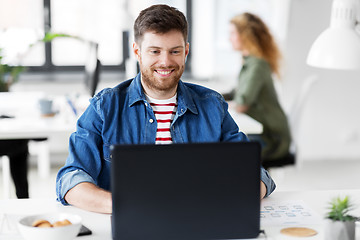 Image showing smiling creative man with laptop working at office