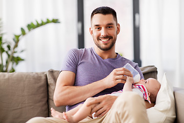 Image showing father feeding baby daughter from bottle at home