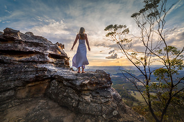 Image showing Standing on a cliff edge with dress blowing in the wind she dreams