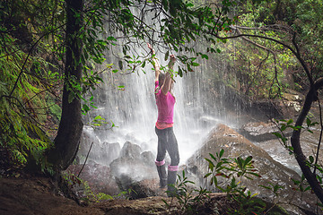 Image showing Female standing in waterfalls with lush ferns, trees in bushland