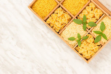 Image showing Box with different types of pasta on marble background