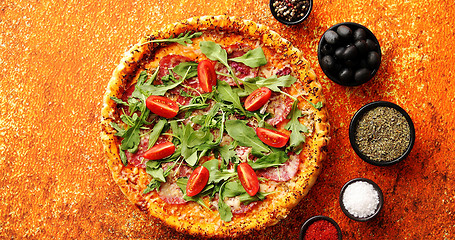 Image showing Tasty pizza on a rusty background with spices, herbs and vegetables