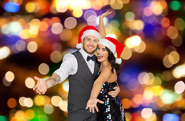Image showing happy couple in santa hats at christmas party