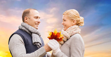 Image showing couple with maple leaves over sunset sky in autumn