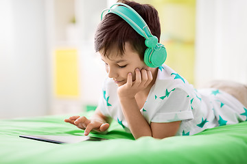 Image showing smiling boy with tablet pc and headphones at home