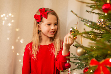 Image showing happy girl in red decorating christmas tree