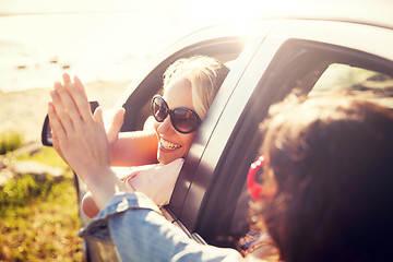 Image showing happy teenage girls or women in car at seaside