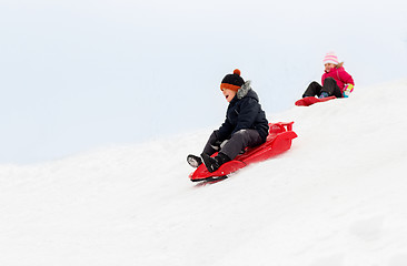 Image showing happy kids sliding on sleds down hill in winter