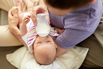 Image showing close up of father feeding baby from bottle