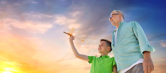 Image showing senior man and boy with toy airplane over sky