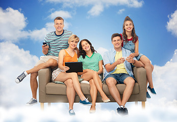 Image showing friends with tablet pc and smartphones sit on sofa