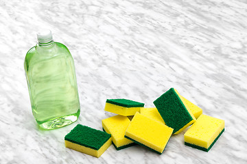 Image showing Dishwashing liquid and sponges on marble kitchen countertop